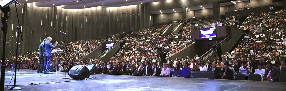 Pastor Doug preaching in Asia in a large auditorium full of people.